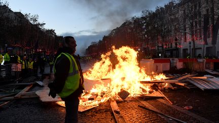 Des "gilets jaunes" devant une barricade enflammée, samedi 24 novembre, sur les Champs-Elysées à Paris. (BERTRAND GUAY / AFP)