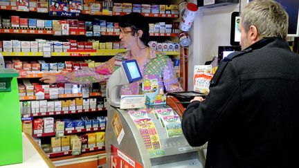 Une buraliste et un client, le 13 janvier 2016, à Montpellier dans l'Hérault. (MICHAEL ESDOURRUBAILH / MAXPPP)