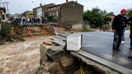 Des habitants observent un pont effondré, dans la commune de Villegailhenc (Aude), le 15 octobre 2018. (ERIC CABANIS / AFP)