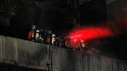 Des pompiers&nbsp;sur un balcon après avoir maîtrisé l'incendie d'un immeuble d'habitation&nbsp;du 19e arrondissement boulevard Macdonald à Paris, le 6 avril 2019. (GEOFFROY VAN DER HASSELT / AFP)