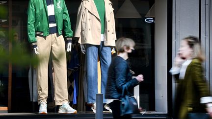 Des personnes passent devant la vitrine d'un magasin de vêtements, le 25 mars 2022. (REMI DUGNE / MAXPPP)