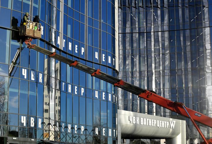 Des ouvriers&nbsp;collent des autocollants du groupe Wagner sur un immeuble de bureaux,&nbsp;le 31 octobre 2022, qui sera bientôt inauguré à Saint-Pétersbourg (Russie). (OLGA MALTSEVA / AFP)