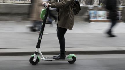 Une femme sur une trottinette électrique, à Paris. (KENZO TRIBOUILLARD / AFP)