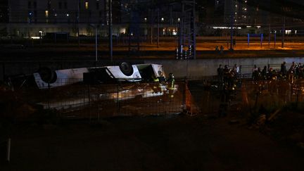 Des pompiers interviennent sur la voie ferrée après la chute d'un bus depuis un viaduc, le 3 octobre 2023, dans la localité de Mestre, à Venise (Italie). (MARCO SABADIN / AFP)