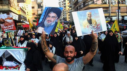 Un manifestant libanais brandit une pancarte à l'effigie d'Hassan Nasrallah, le chef du Hezbollah (à gauche) à Sidon, dans le sud du Liban, le 28 octobre 2023. (MAHMOUD ZAYYAT / AFP)