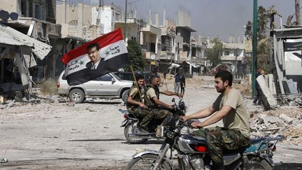 Des soldats de l'arm&eacute;e loyaliste brandissent un drapeau syrien et un portrait de Bachar Al-Assad, &agrave; Qousseir,&nbsp;le 5 juin 2013. (MOHAMED AZAKIR / REUTERS)