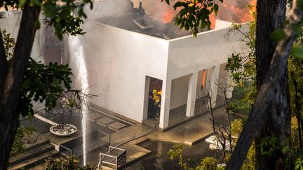 Plus de 12 000 maisons sont menacées par les flammes dans la région de Los Angeles. Comme celle-ci, située à l'extrémité du luxueux quartier de Bel Air, que les pompiers tentaient de sauver de l'incendie "Skirball", le 6 décembre 2017. (KYLE GRILLOT / AFP)