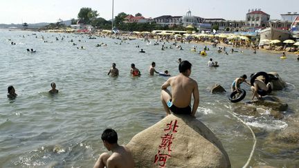 Des vacanciers chinois sur la plage de Beidahe (Chine), en août 2003 (MICHAEL REYNOLDS / EPA)