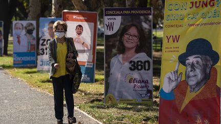 Une femme passe devant des affiches pour l'élection des membres de l'Assemblée constituante, à Santiago le 12 mai 2021. (MARTIN BERNETTI / AFP)