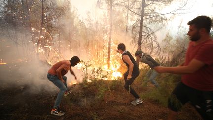 Des riverains participent, à mains nues, à la lutte contre les incendies de forêt qui ont éclaté à Antalya alors que les opérations d'extinction terrestres et aériennes se poursuivent le 1er août 2021, en Turquie. Les autorités turques poursuivent leurs efforts inlassables pour contenir les incendies de forêt qui ont éclaté dans diverses parties du pays, en particulier dans les régions du sud. (SULEYMAN ELCIN / ANADOLU AGENCY / AFP)