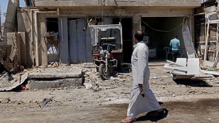 Des civils inspectent les d&eacute;gats apr&egrave;s une attaque &agrave; la voiture pi&eacute;g&eacute;e pr&egrave;s de Bagdad, le 25 avril 2013. (HADI MIZBAN / AP / SIPA)