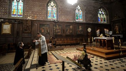 Un prêtre&nbsp;accueille une paroissienne dans l'église Saint-Jacques d'Illiers-Combray&nbsp;(Eure-et-Loir), le 15 novembre 2020. (JEAN-FRANCOIS MONIER / AFP)