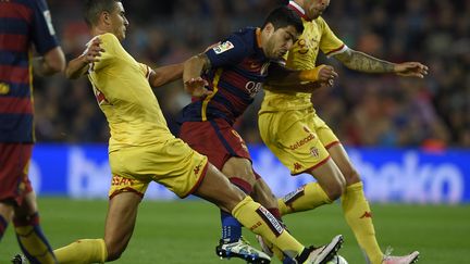 Luis Suarez (Barcelone) tente le passage en force entre deux défenseurs de Gijon (LLUIS GENE / AFP)