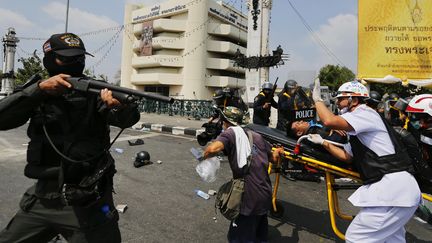 Un policier prot&egrave;ge l'&eacute;vacuation d'un coll&egrave;gue bless&eacute; lors d'affrontements contre les manifestants anti-gouvernementaux &agrave; Bangkok (Tha&iuml;lande), le 18 f&eacute;vrier 2014. ( DAMIR SAGOLJ / REUTERS)