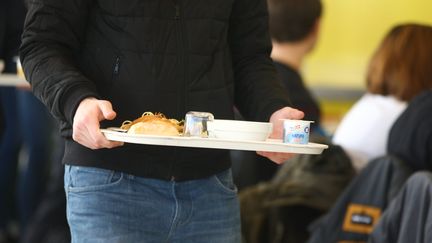 Un jeune homme portant son plateau de repas, à la cantine scolaire. (VINCENT VOEGTLIN / MAXPPP)