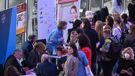 Des réfugiés&nbsp;ukrainiens&nbsp;prennent des informations dans un salon de l'emploi organisé par la Chambre de l'industrie et du commerce à Berlin, le 2 juin 2022. (JOHN MACDOUGALL / AFP)