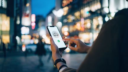 Une jeune femme utilise une application de VTC. (Photo d'illustration) (D3SIGN / MOMENT RF / GETTY IMAGES)