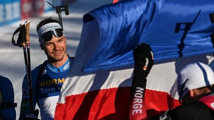 Emilien Jacquelin avec le drapeau bleu-blanc-rouge après sa victoire sur le mass start du Grand-Bornand, dimanche 19 décembre. (OLIVIER CHASSIGNOLE / AFP)