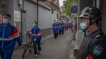 Des élèves portant des masques passent devant un agent de sécurité à leur sortie du collège, à Pékin, en Chine, le 11 mai 2020.  (ROMAN PILIPEY / EPA)