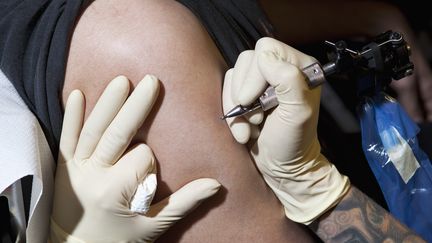 Un artiste-tatoueur en train de tatouer le bras d'un homme, le 14 juin 2012..&nbsp; (HALFDARK / FSTOP)