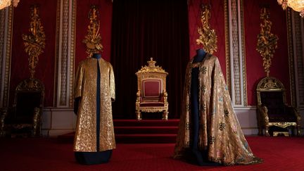 Les vêtements de couronnement, comprenant la Supertunica (à gauche) et le manteau impérial (à droite), sont exposés dans la salle du trône du palais de Buckingham, à Londres, le 26 avril 2023. Les vêtements seront portés par le roi Charles III de Grande-Bretagne lors de son couronnement à l'abbaye de Westminster le 6 mai. (VICTORIA JONES / POOL / AFP)