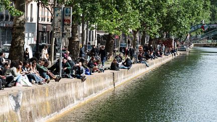 De jeunes Parisiens se réunissent le long du canal Saint-Martin, le 11 mai 2020 à Paris, à l'occasion de la première journée de déconfinement.&nbsp; (SAMUEL BOIVIN / NURPHOTO / AFP)