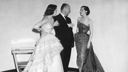 Le couturier Christian Dior avec deux de ses mannequins avant la présentation de sa dernière collection, le 24 avril 1950. (AFP)