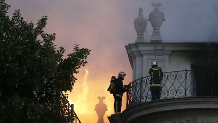 Des pompiers tentent d'&eacute;teindre un incendie qui ravage l'h&ocirc;tel Lambert sur l'&icirc;le Saint-Louis &agrave; Paris, le 10 juillet 2013. (KENZO TRIBOUILLARD / AFP)