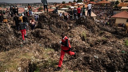 A Red Cross worker runs to get help after a garbage dump collapsed in Kampala, Uganda, on August 10, 2024. (BADRU KATUMBA / AFP)