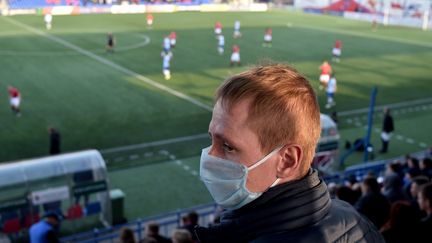 Un supporter du FC Minsk porte un masque de protection, alors qu'il assiste à un match du championnat de football, contre le FC Dinamo-Minsk, le 28 mars 2020. (SERGEI GAPON / AFP)