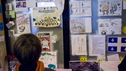 Un enfant regarde des dessins r&eacute;alis&eacute;s en hommage aux victimes de "Charlie Hebdo",&nbsp;pr&egrave;s du si&egrave;ge de l'hebdomadaire, &agrave;&nbsp;Paris, le&nbsp;9 janvier 2015. (  MAXPPP)