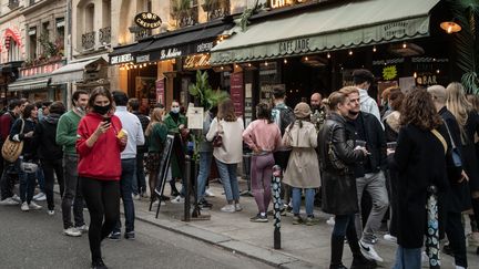 Des Parisiens profitent des températures clémentes dans la capitale, le 21 février 2021, rue de Buci (6e arrondissement). (BERTRAND GUAY / AFP)