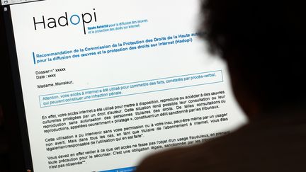 Un internaute lit un courrier d'avertissement de la Hadopi après un téléchargement illégal. (THOMAS COEX / AFP)