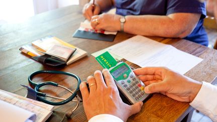 Un m&eacute;decin pratique la t&eacute;l&eacute;transmission avec la carte vitale de son patient en Dordogne, le 7 juin 2012.&nbsp; (BURGER / PHANIE / AFP)