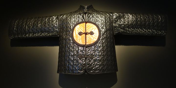 Veste de soir automne-hiver 1977. Cette veste brillante à la staure imposante est frappée d'un médaillon qui fait allusion aux badges impériaux, ainsi qu'au mobilier chinois dont les vantaux de portes sont ornés d'un motif circulaire en laque. 
