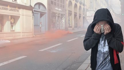 Un manifestant protège son visage des gaz lacrymogènes lancés par la police, le 31 mars à Rennes.&nbsp; (JEAN-FRANCOIS MONIER / AFP)