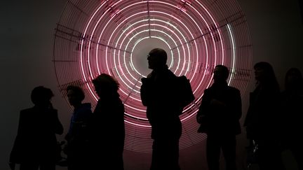 Des visiteurs de la foire Art Basel devant une oeuvre de Carsten Holler, "Decimal Clock (White and Pink)", Bâle (Suisse) le 12 juin 2019 (FABRICE COFFRINI / AFP)