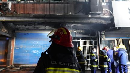 Un pompier devant un magasin incendié en Chine, le 24 janvier 2024. (ZHOU MI / XINHUA / AFP)