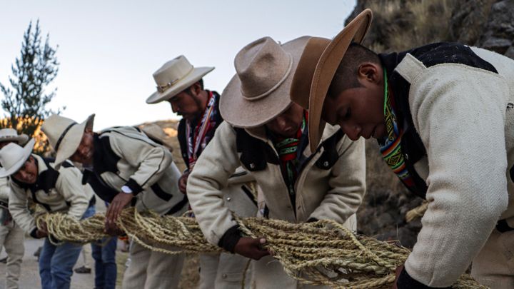 Des hommes nouent des cordes et les tendent à la force de leurs bras pour fabriquer le pont Q'eswachaka. (CHRISTIAN SIERRA / AFP)