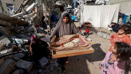 A woman carrying bread next to destroyed houses in Rafah, southern Gaza Strip, December 11, 2023, amid continued fighting between Israel and Hamas.  (MOHAMMED ABED / AFP)