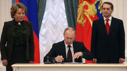 Le pr&eacute;sident russe Vladimir Poutine signe la loi rattachant la Crim&eacute;e &agrave; la F&eacute;d&eacute;ration de Russie, vendredi 21 mars au Kremlin.&nbsp; (SERGEI CHIRIKOV / POOL / AFP)