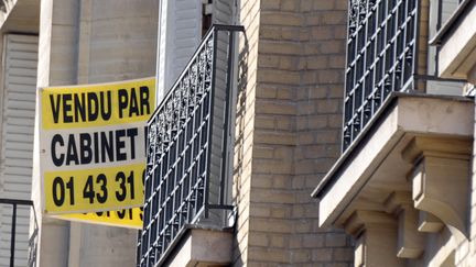 Panneau de vente posé sur la rambarde d'une fenêtre. (ERIC PIERMONT / AFP)