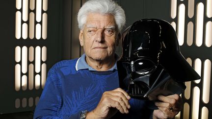 L'acteur Dave Prowse pose à côté d'un casque de Dark Vador, le 28 mai 2016, lors d'une foire à Cologne (Allemagne). (FMB / WENN.COM / SIPA)