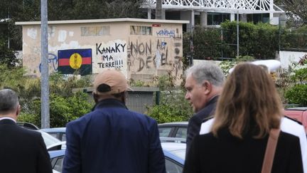 Le ministre des Outre-mer, François-Noël Buffet à Nouméa,le 16 octobre 2024, lors d'une cérémonie de bienvenue au Sénat Coutumier de la Nouvelle-Calédonie. La photo montre un drapeau peint sur un mur du FLNKS, le Front de libération nationale kanak et socialiste, près d'un graffiti "Kanaky, ma Terre !!" (THEO ROUBY / AFP)