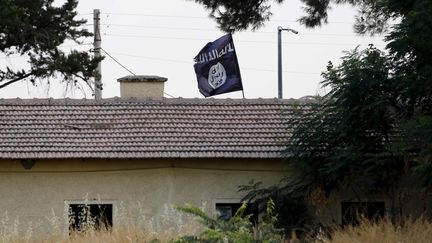 Le drapeau du groupe Etat islamique flotte sur un b&acirc;timent de Jarablus (Syrie), &agrave; la fronti&egrave;re avec la Turquie, le 1er ao&ucirc;t 2015. (MURAD SEZER / REUTERS)