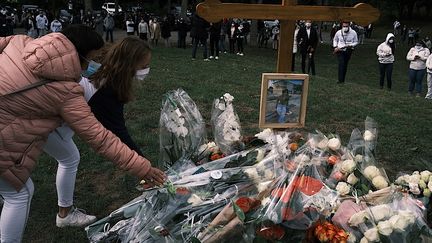 Des bouquets de fleurs devant la photo de Victorine Dartois, lors de la marche blanche organisée à Villefontaine (Isère), le 4 octobre 2020.&nbsp; (JEAN-PHILIPPE KSIAZEK / AFP)