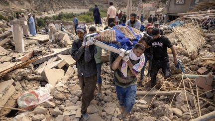 Des secouristes portent une victime décédée dans le séisme, à Imi N'Tala près d'Amizmiz, au centre du Maroc, le 10 septembre 2023. (FADEL SENNA / AFP)