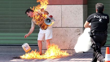 Un policier tente de sauver un homme qui s'immole par le feu devant une banque &agrave; Thessalonique (Gr&egrave;ce), le 16 septembre 2011. (NONTAS STYLIANIDI / AFP)