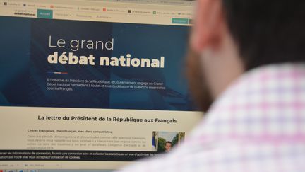 Un homme devant la page d'accueil du grand débat, sur l'écran d'un ordinateur. (JEAN-CHRISTOPHE BOURDILLAT / RADIO FRANCE)