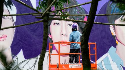 Pour les dix ans du groupe coréen BTS, un artiste crée une grande peinture murale à Séoul, le 12 juin 2023. (ANTHONY WALLACE / AFP)